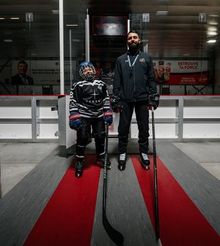 Nick Orlando and a young hockey player posing for a photo in front of the ice at Hockey Etcetera