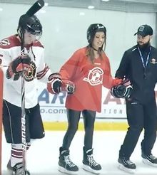Nick Orlando and Kevin Hylland holding Caitlyn Howe's hands while teaching her hockey