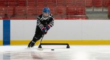 Young kid skating around a hockey dangler with a puck