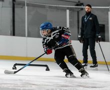 A kid practicing with coach Nick Orlando at Hockey Etcetera