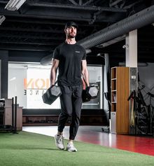 Tanner Kichler lifting 2 x 100lbs weights inside Junxion Performance gym