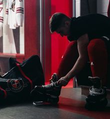 A player tieing his skates at Hockey Etcetera in a low-lit dressing room