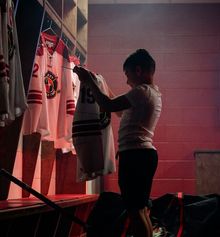 A kid holding up and starting at a Hockey Etcetera hockey jersey in the dressing room