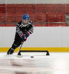 Young kid skating around a hockey dangler with a puck