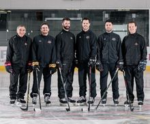 A group of Hockey Etcetera trainers smiling on the ice