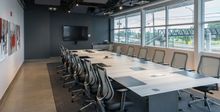 Hockey Etcetera board room table lined with grey office chairs and a TV on the far wall