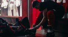 A player tieing his skates at Hockey Etcetera in a low-lit dressing room