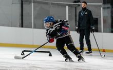 A kid practicing with a coach at Hockey Etcetera